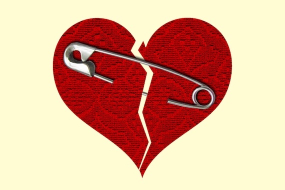 a red heart with a jagged line down the middle and a safety pin holding it together