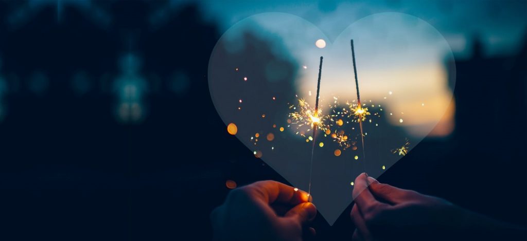 2 hands holding sparklers framed by a heart