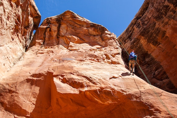 a person using ropes to climb a cliff face