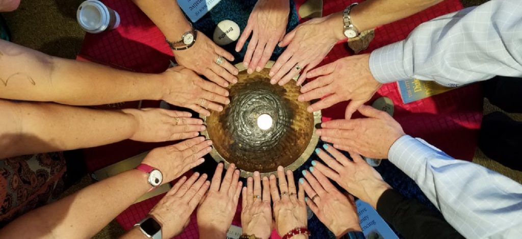 14 hands touching the rim of a large, gold chalice