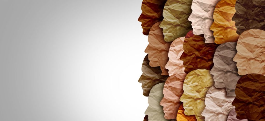 paper cutouts of face silouettes in many different shades of brown and tan overlapping and facing left.