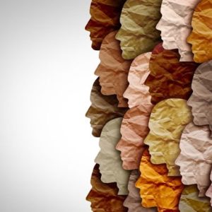 paper cutouts of face silouettes in many different shades of brown and tan overlapping and facing left.