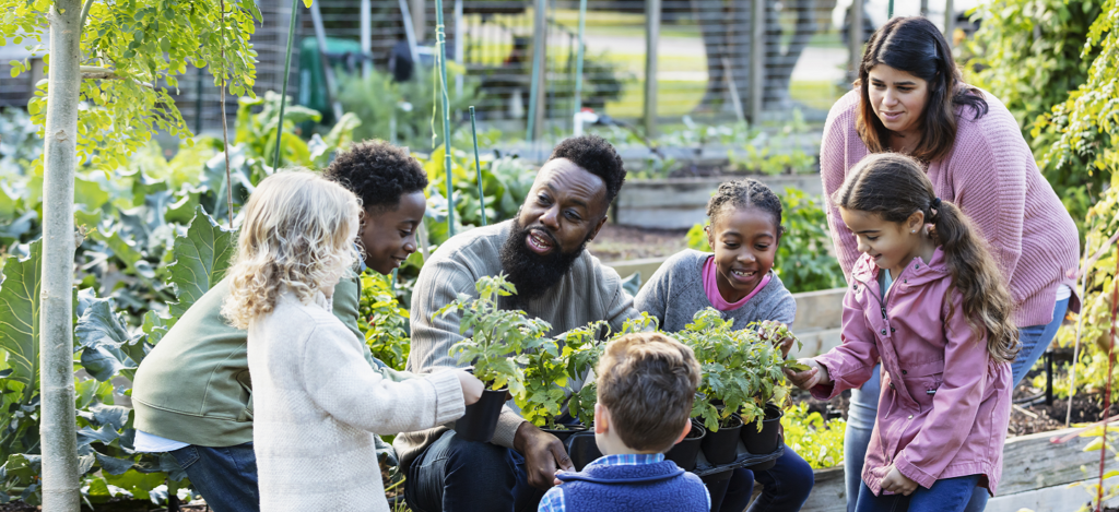 Community Garden with Black man teaching a group of black, brown and white children