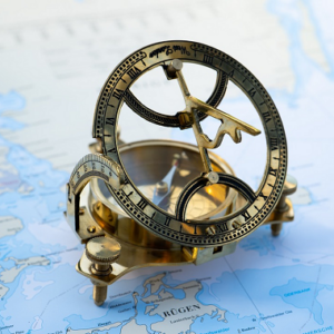 An antique navigation device sitting on a world map
